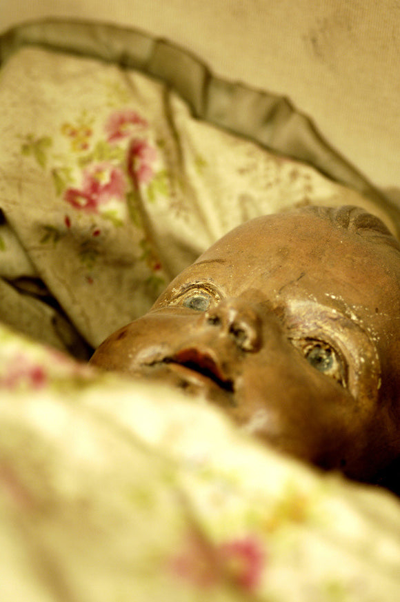 Close up of doll in a C19th cradle, part of the Charles Wade collection, in Seventh Heaven at Snowshill Manor