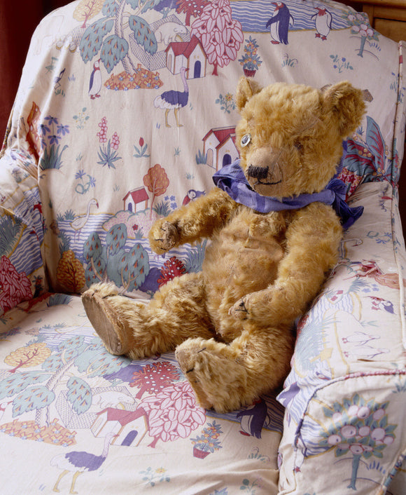Lord Wraxall's Teddy Bear sitting on a chair covered with a nursery print in the Day Nursery at Tyntesfield